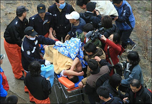 삼성그룹 계열사인 (주)에스원의 해고노동자들이 부당해고 철회를 요구하며 마포에서 여의도까지 한강을 헤엄쳐 건너는 수상시위를 벌였다. 여의도 둔치에 도착한 뒤 한 시위자가 탈진해서 들것에 실리고 있다. 